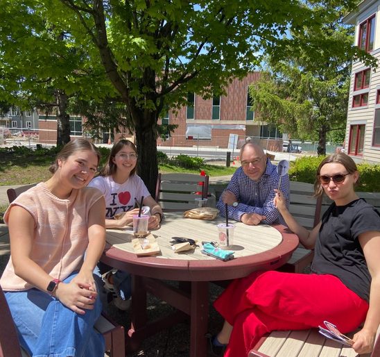 A group of SOAN students and faculty enjoying banh mi and bubble tea on the Weitz patio at the spring '24 New Majors Gathering.