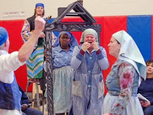 Actors perform with a wooden theater set