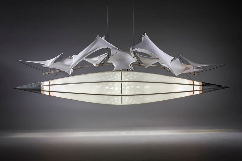 A suspended steel motorized sculpture containing lights inside a polyester-covered frame