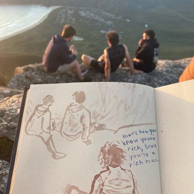 Three young men sat atop Mt. Oberon in Wilson’s Promontory National Park at sunset.