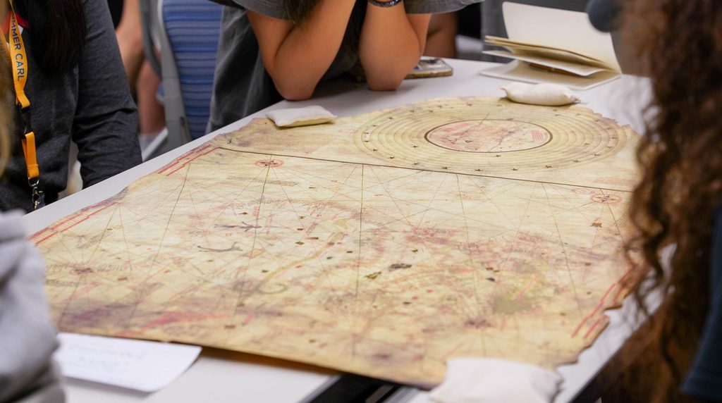 students admire an ancient map on a table