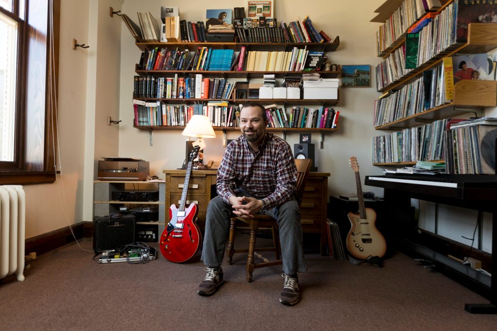Andy Flory in his office, surrounded by record albums and guitars
