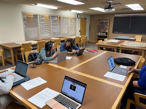 4 people sitting around a table with computers