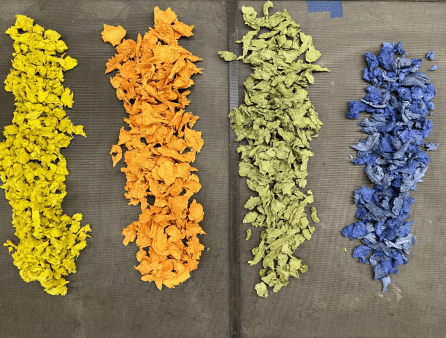 image of four piles of colored paper bits - yellow, orange green and blue