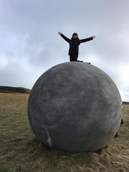 Student on Ball in Iceland, Tali Emlen '22 on the Orbis et Globus in Grímsey. The landmark marks the Arctic Circle.