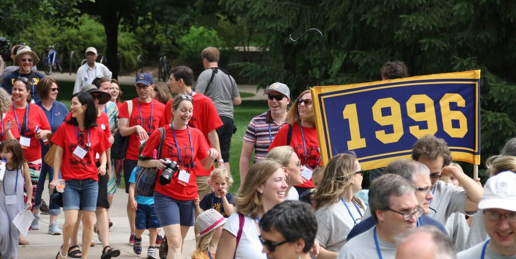 A group of people in matching t-shirts walking with a banner reading "1996"