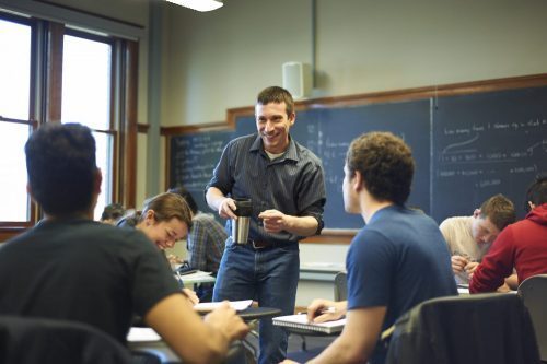 A professor jokes with students during study