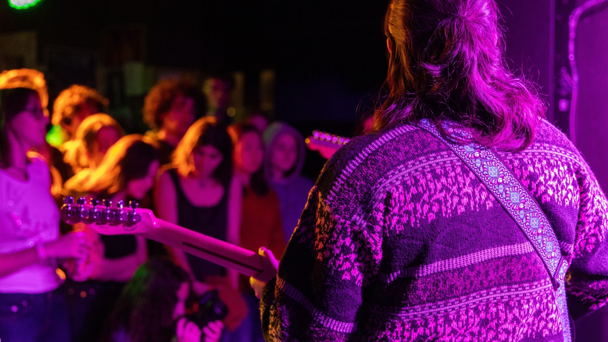 Student playing guitar in purple light
