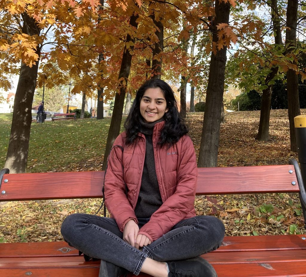 Suhani Thandi '23 seated on a red bench in the trees