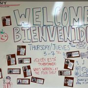 Whiteboard with Spanish and English writing Welcome at the Northfield Community Education Center (NCEC) Food Shelf