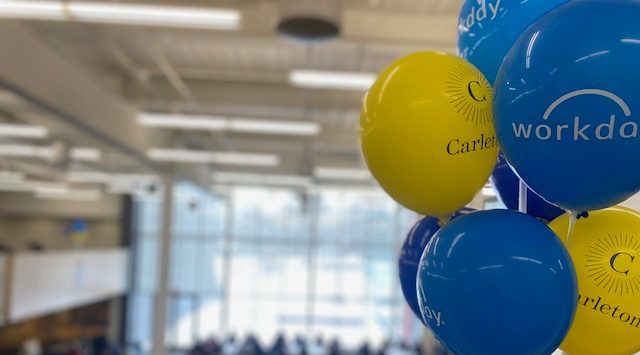 blue and yellow balloons in front of large audience