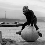 Person climbs around rocks on the shore