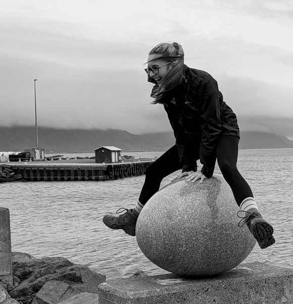 Person climbs around rocks on the shore