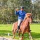 Person riding a horse while holding a mug of beer