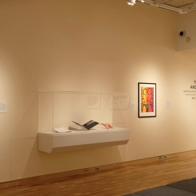 A gallery wall with a large, horizontal glass case flanked by two framed pictures. The glass contains an open book. The words “To Have and to Hold” are printed on the wall to the right of the art.