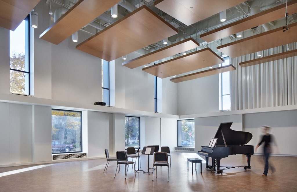 Image of Shackel Hall, a Music Dept. rehearsal space, with a piano, music stands, and chairs.