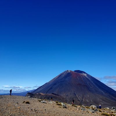 A volcano and a clear blue sky, with people in the foreground