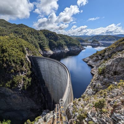 An artificial dam surrounded by trees and a cloudy sky