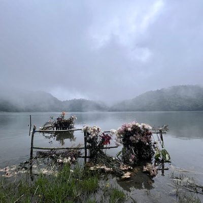 A misty lake with ceremonial flowers in the foreground
