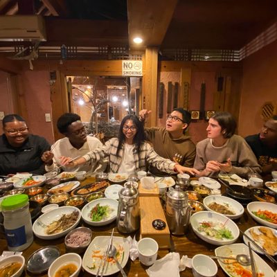 A group of students sitting at a table full of Korean cuisine
