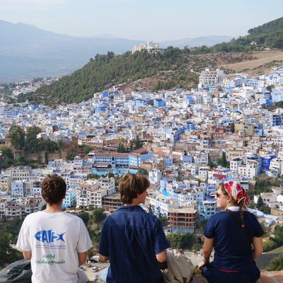 Three students sit on a ledge overlooking a city