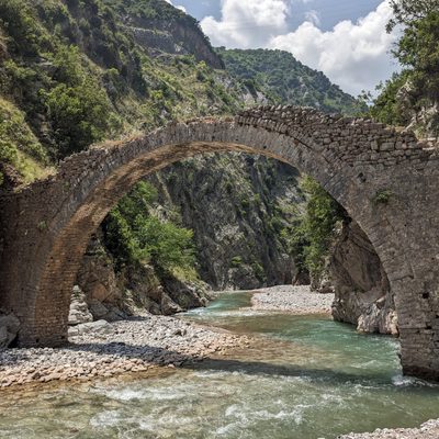 A worn-down stone bridge over a river