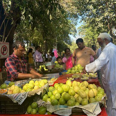 A group of people in a food market at a guava stall