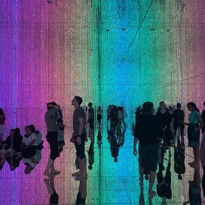 A crowd of people standing in a rainbow-lit room