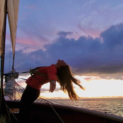 A student leaning back from the mast of a ship