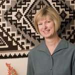 Bev nagel stands in front of a woven wall tapestry