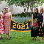Four members of the Class of 2021 stand next to the maize and blue class banner, which reads 