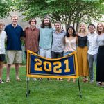Eleven members of the Class of 2021 stand behind the maize and blue class banner, which reads 