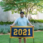 One member of the Class of 2021 stands behind the maize and blue class banner, which reads 