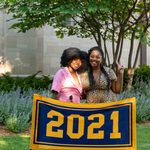 Two members of the Class of 2021 stand behind the maize and blue class banner, which reads 