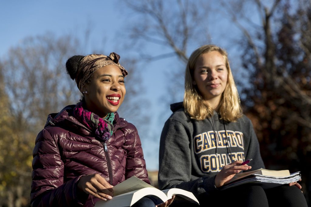 Two students read books outside on campus