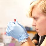 student closely looking at a vile