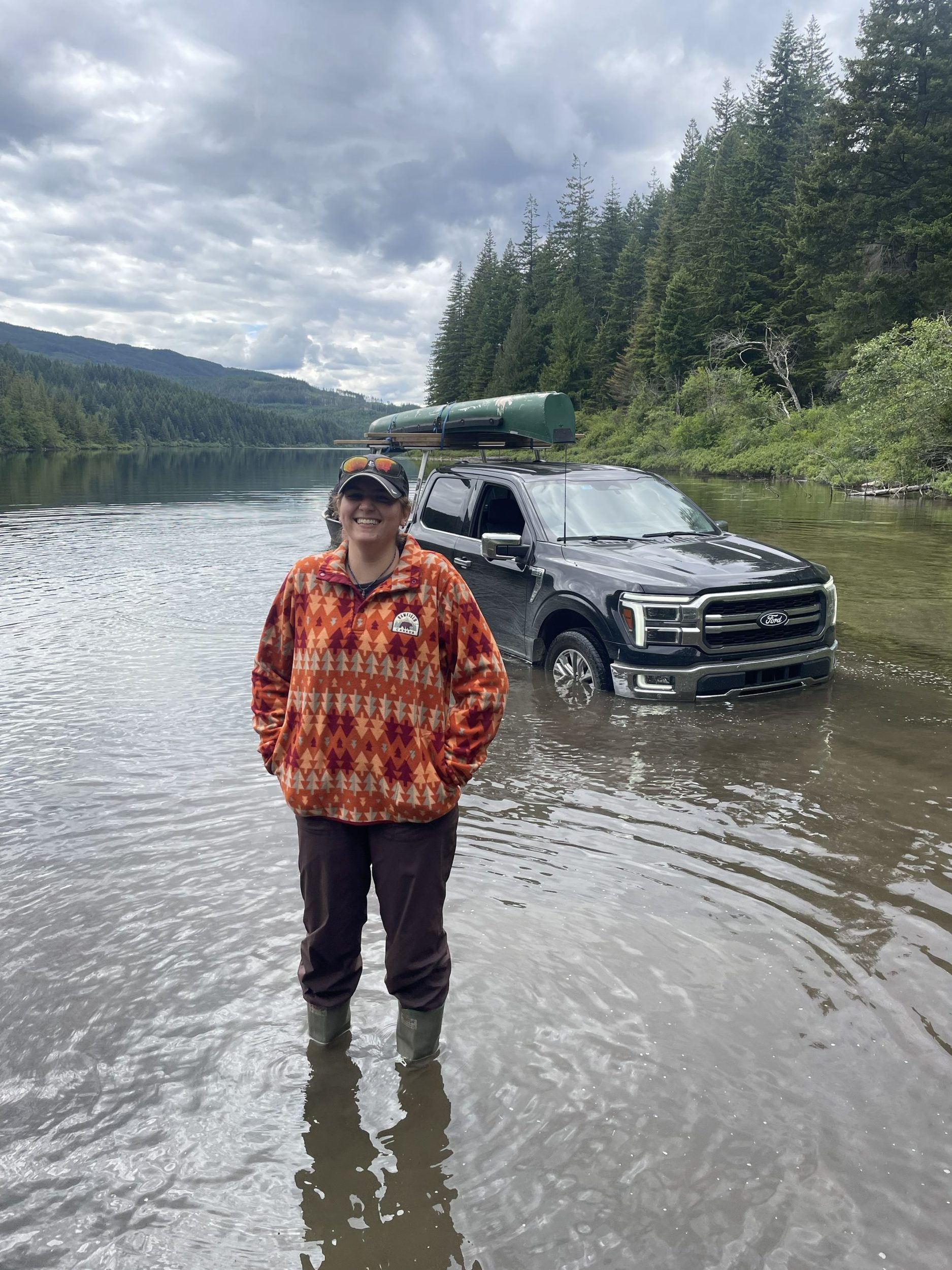 Penelope Steffen standing in a mountain lake in front of a partially submerged truck.