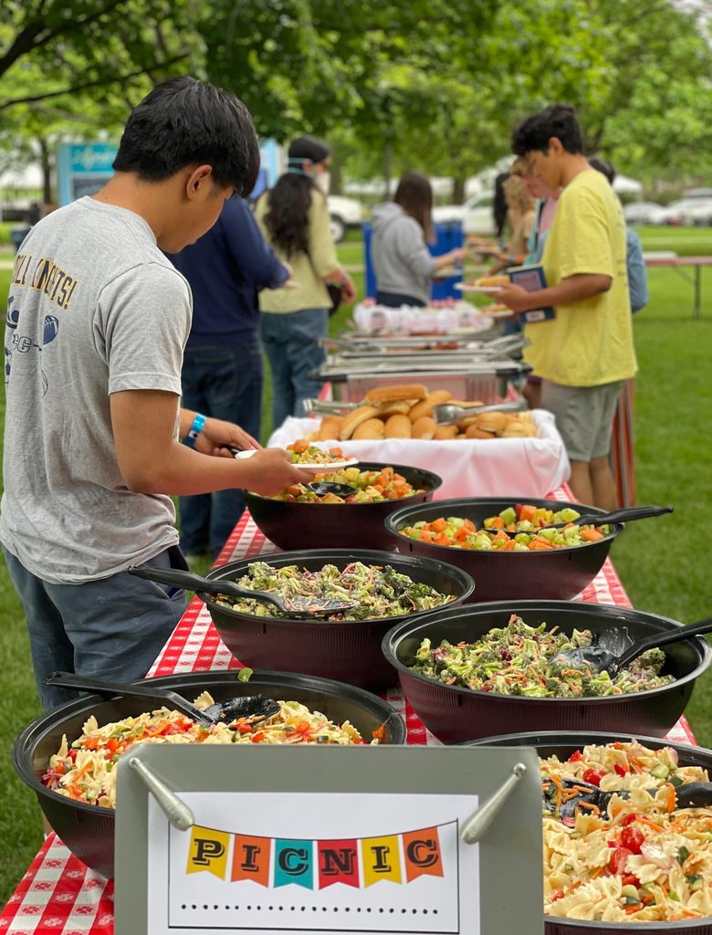 students fill their plates at an outdoor picnic