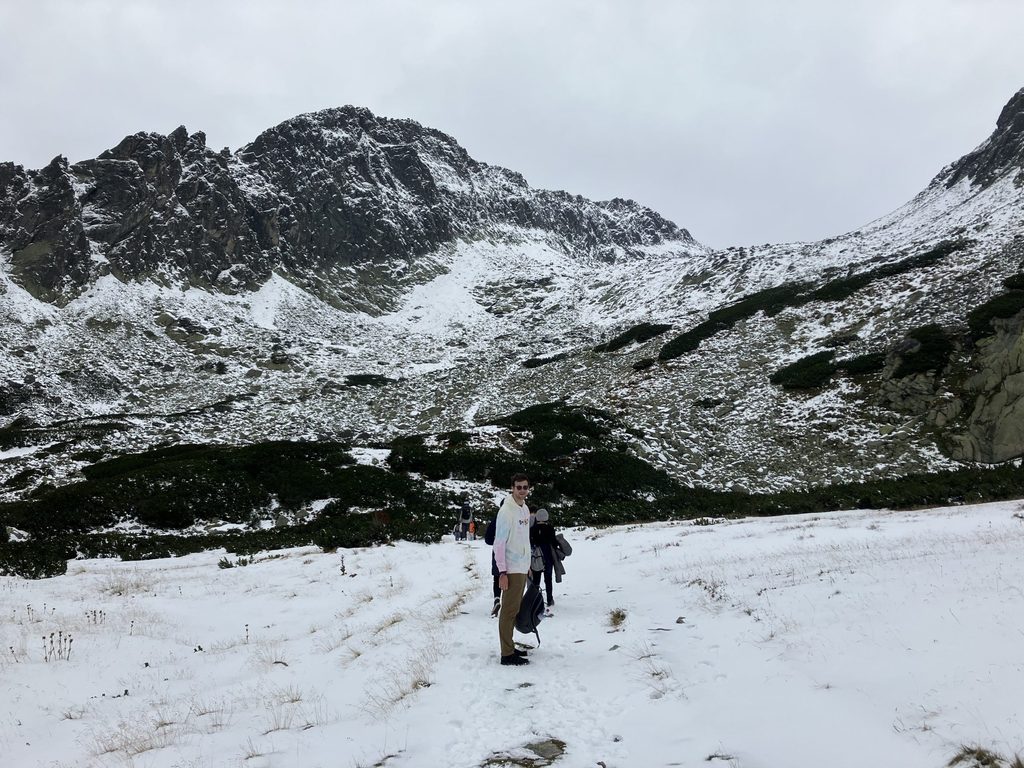 Hiker looks back at camera with wide angle mountain view in background.