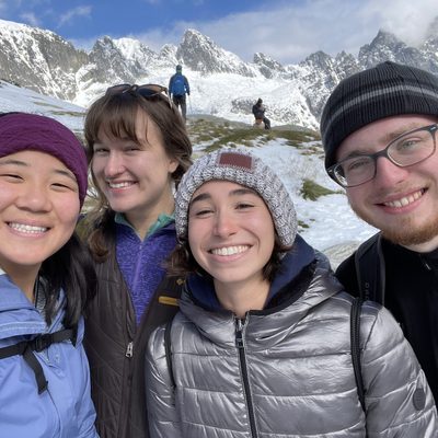 Four people smiling with snowy mountains in the background