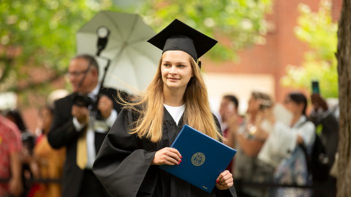 A graduate holding her diploma