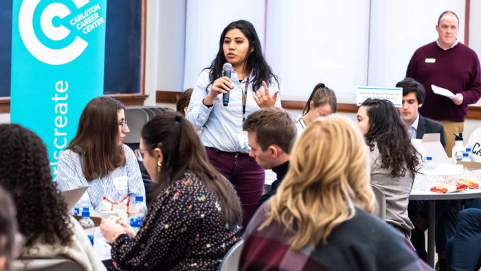 A woman holds a microphone in a room full of people