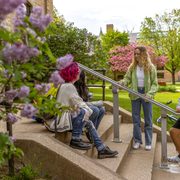 A group of Carleton students sitting on the Chapel steps with spring blooms in the frame