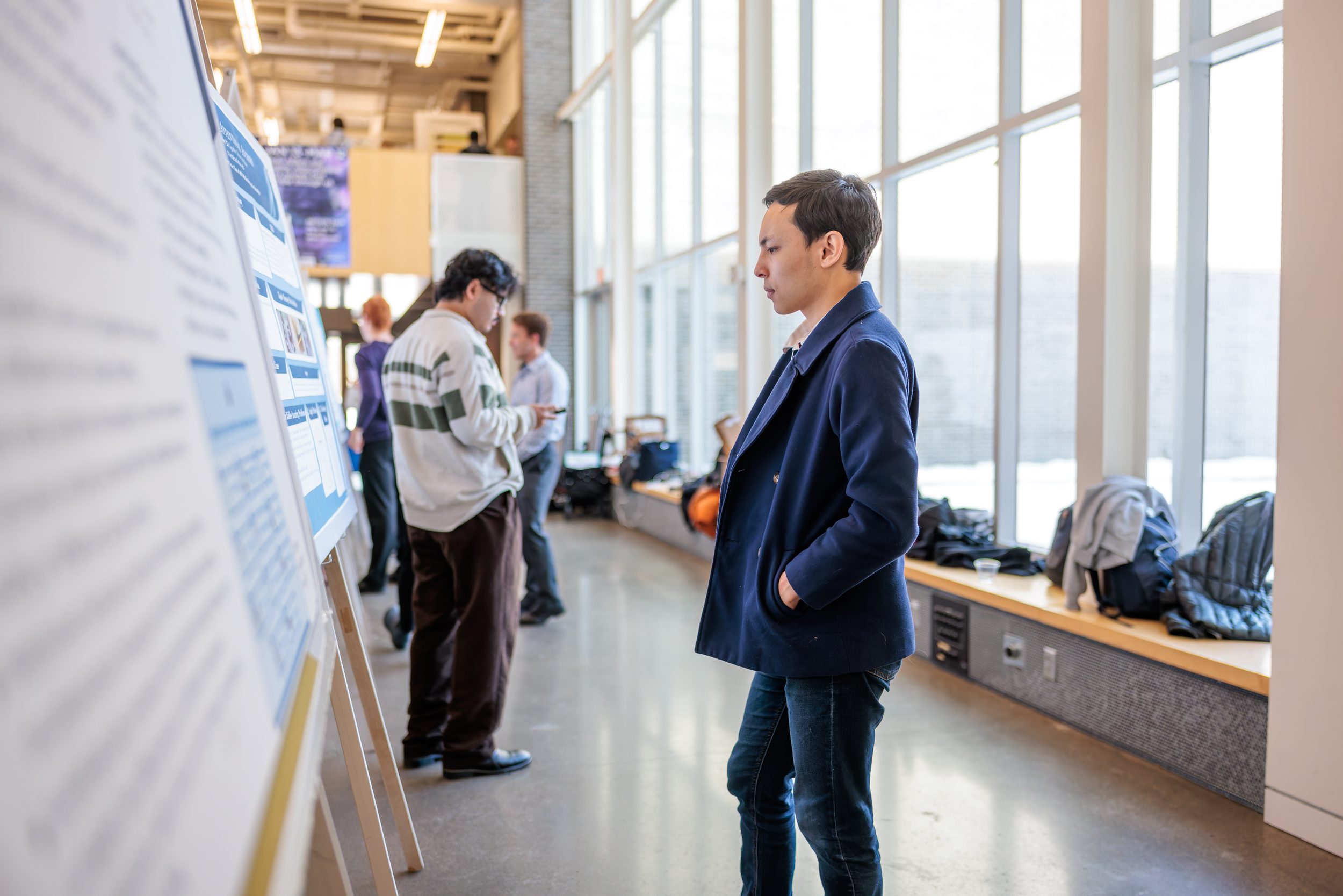 An alumnus reading a student's internship poster at a poster session