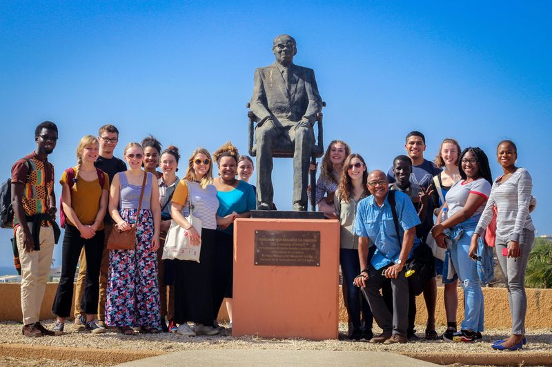 students aorund important person statue Senegal