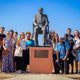 students aorund important person statue Senegal