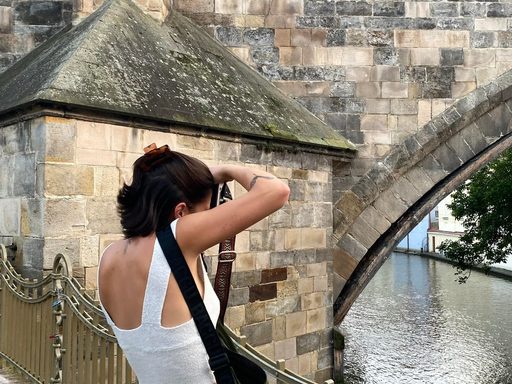 Tori Aguado standing in front of bridge taking a picture