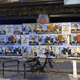 a wall covered in cat posters under a bridge with a bicycle