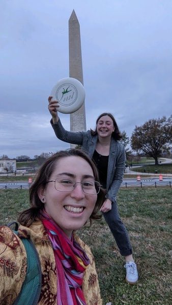 two students holding a frisbe infront of the washington monument