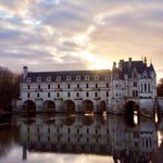 a castle built on a body of water in the sunset